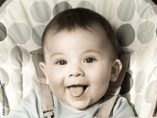 Portrait of small caucasian baby boy sitting at the chear photo