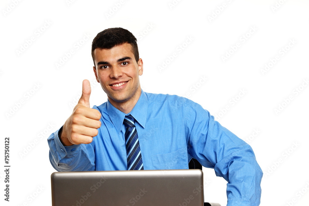 Young businessman sits at the laptop and shows you thumb up Young businessman sits at the laptop and shows you thumb up