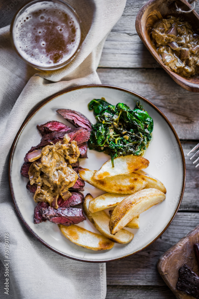 Steak with baked botatoes and green salad on wooden background