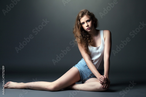 Skinny young model posing in studio, on gray
