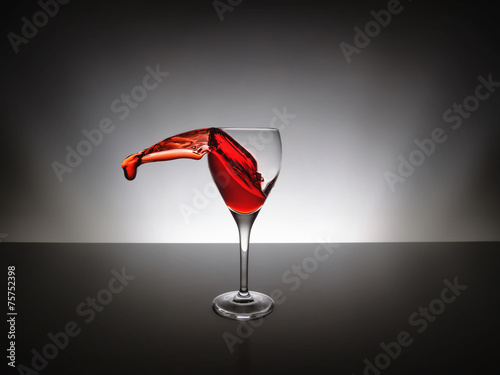 Glass of red wine with splash over black background