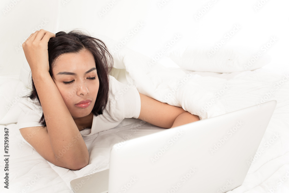 Smiling woman using a laptop while lying on her bed Smiling woman using a laptop while lying on her bed