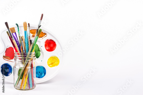 isolated paints palette and paints brushes in a glass