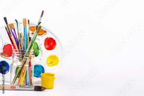isolated paints brushes in a glass and yellow water paint