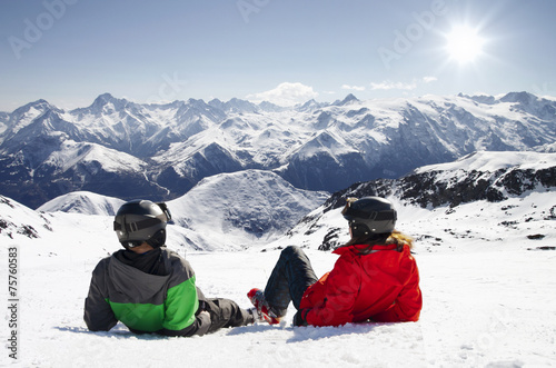 Young happy couple lying in snowy mountains