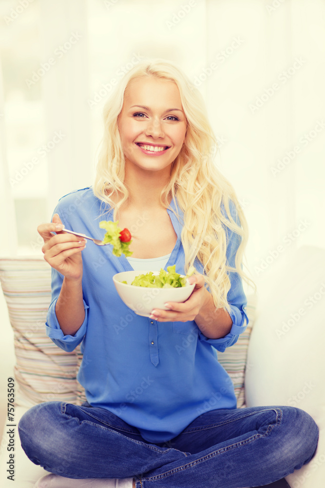smiling young woman with green salad at home