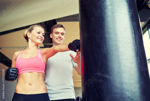 smiling woman with personal trainer boxing in gym © Syda Productions