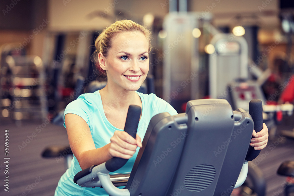 smiling woman exercising on exercise bike in gym smiling woman exercising on exercise bike in gym