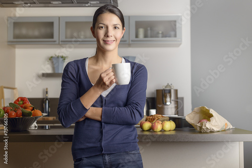 Glückliche zufriedene Hausfrau trinkt Kaffee