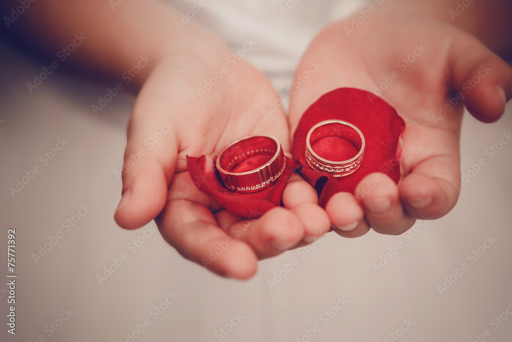 Wedding rings lie on children's palms with petals of roses Wedding rings lie on children's palms with petals of roses