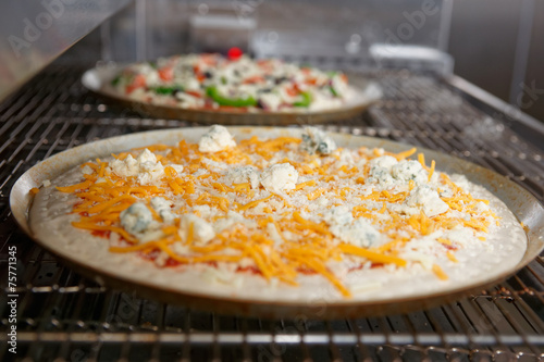 Cheese pizza entering the industrial oven