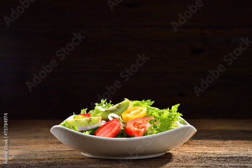 Fruit and vegetable salad in a bowl on wooden background