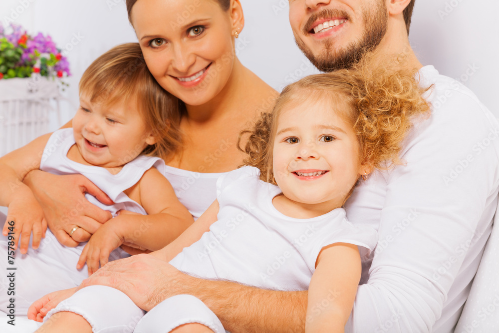 Happy parents with two adorable children on bed Happy parents with two adorable children on bed