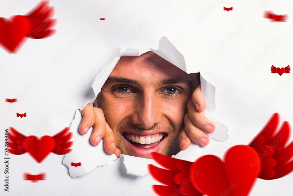 Composite image of young man looking through paper rip Composite image of young man looking through paper rip