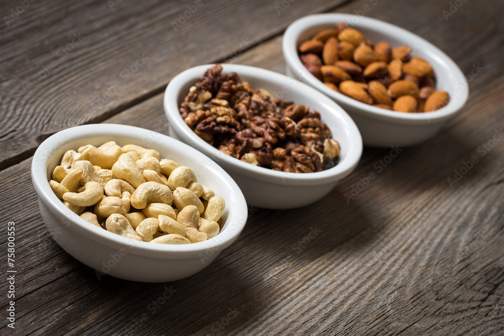 Sorted nuts in white bowls on wooden background Sorted nuts in white bowls on wooden background