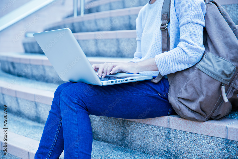 Naklejka premium Young woman using laptop on steps outdoors