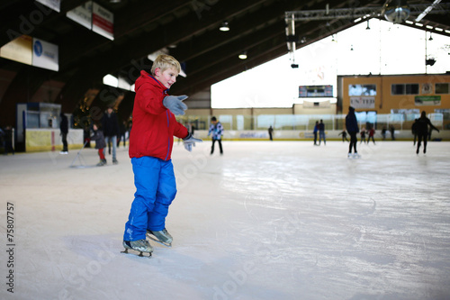 Happy school boy having fun at indoors skating rink