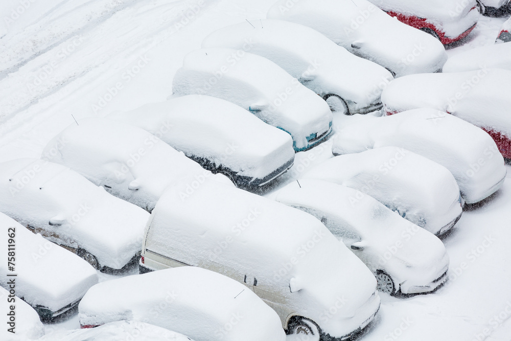 Fototapeta premium Cars covered in snow on a parking lot in the residential area 