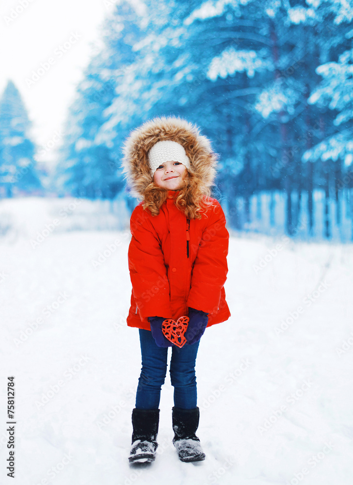 Child with heart in hands outdoors in winter snowy day