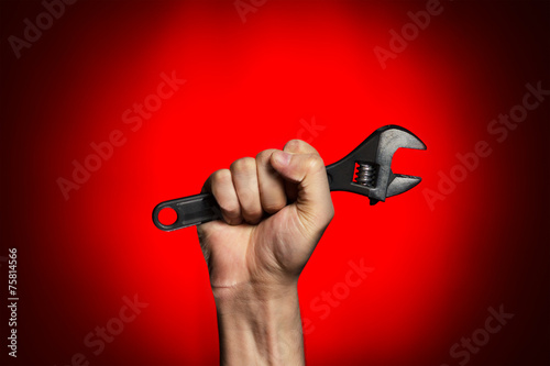 Fotografía man holding adjustable wrench over red