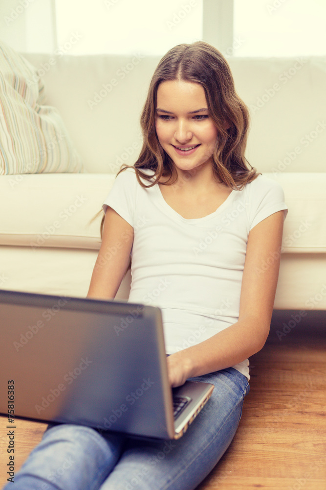 smiling teenage girl with laptop computer at home