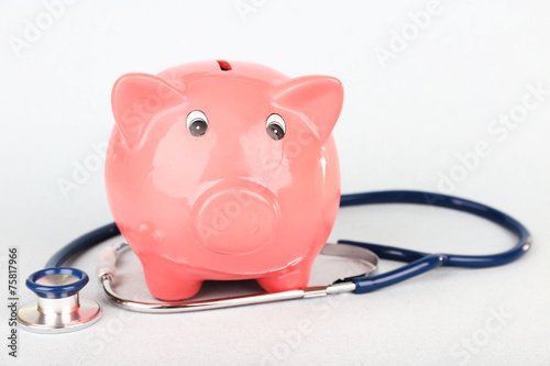 Pink piggy bank with stethoscope isolated on white