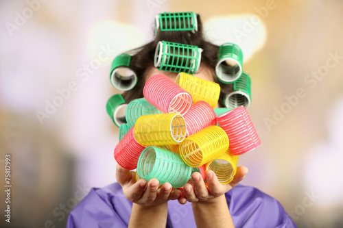 Girl in hair curlers on bright background