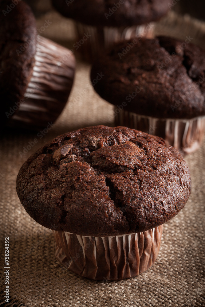 Chocolate cake muffins on a table. Dark lighting Chocolate cake muffins on a table. Dark lighting