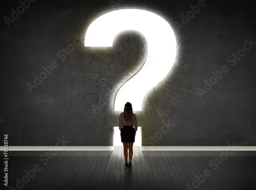 Business woman looking at wall with a bright question mark photo