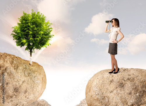Businesswoman on rock mountain with a tree