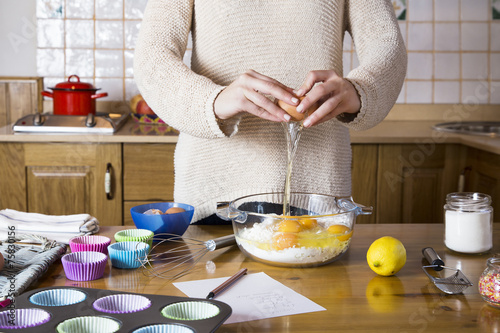 Woman hands breaking an egg to make cupcakes