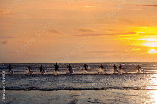 Group of young surfers on the beach, surfin on sunset