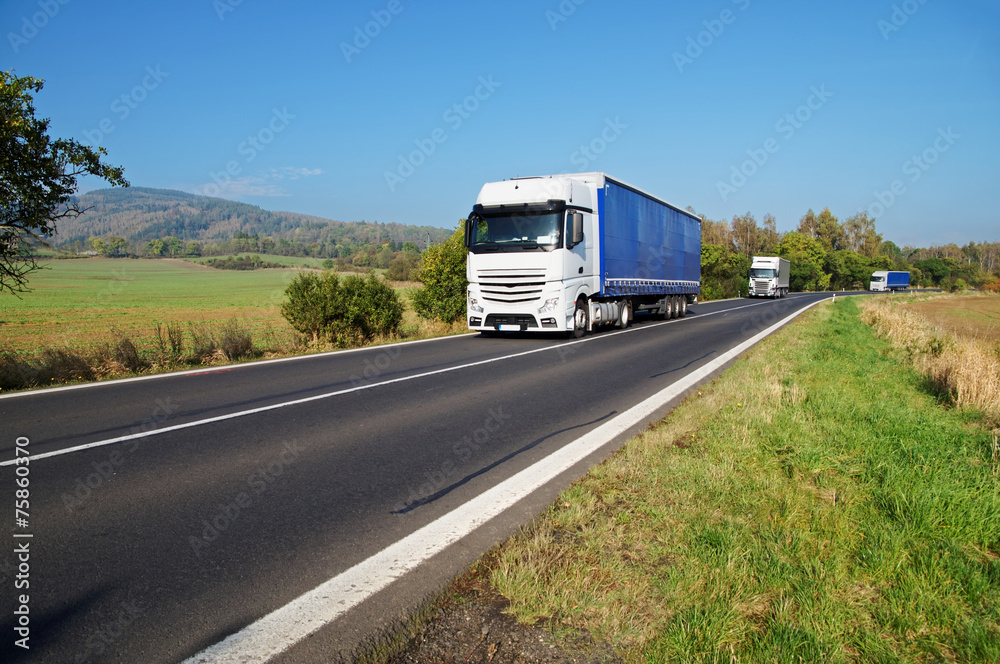 Three white trucks on the road in the countryside Three white trucks on the road in the countryside