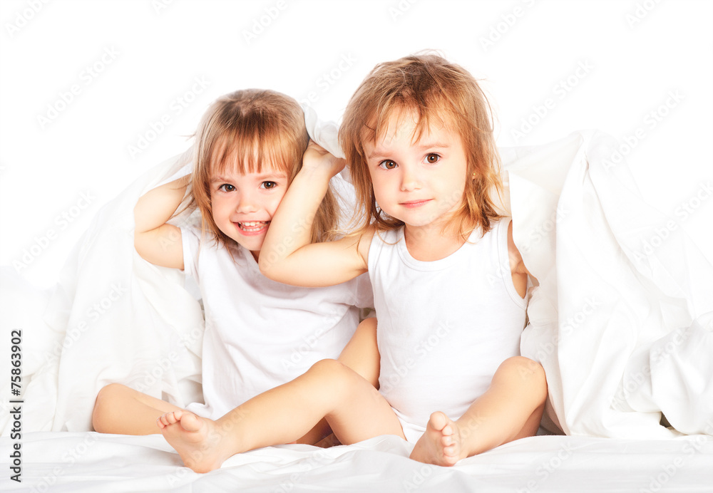 happy little girls twins sister in bed having fun happy little girls twins sister in bed having fun