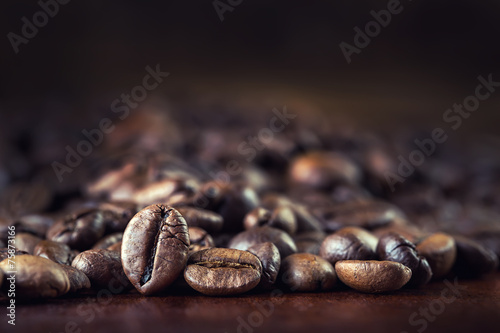 Roasted coffee beans spilled freely on a wooden table.Coffee tim