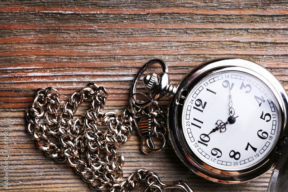 Silver pocket clock on wooden table Silver pocket clock on wooden table