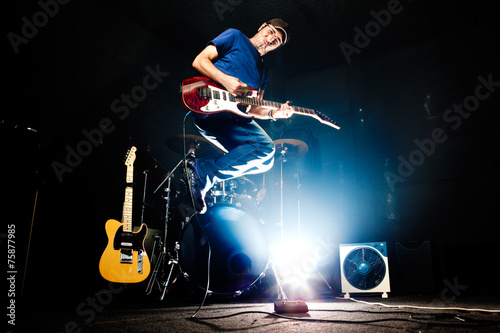 Live music.Rock band rehearsal.Funny time.Guitar player jumping photo