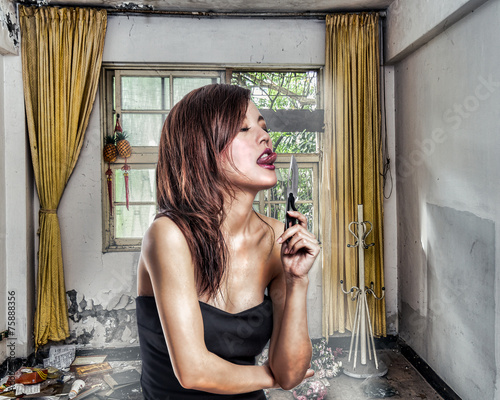 Chinese woman in abandoned aprtment about to lick a knife photo