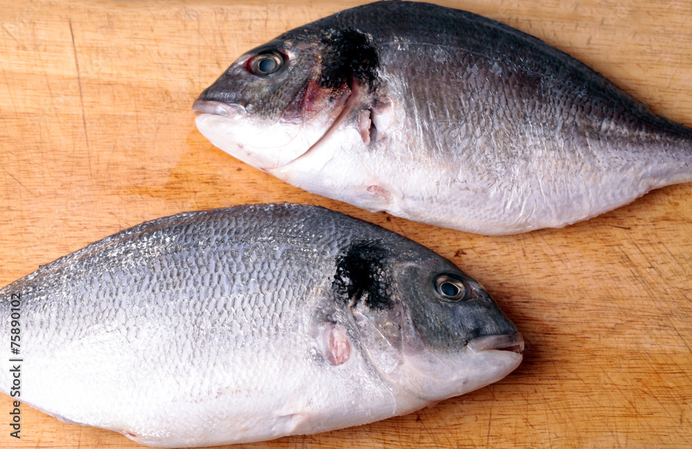 Two uncooked fishes dorado on wood background Two uncooked fishes dorado on wood background