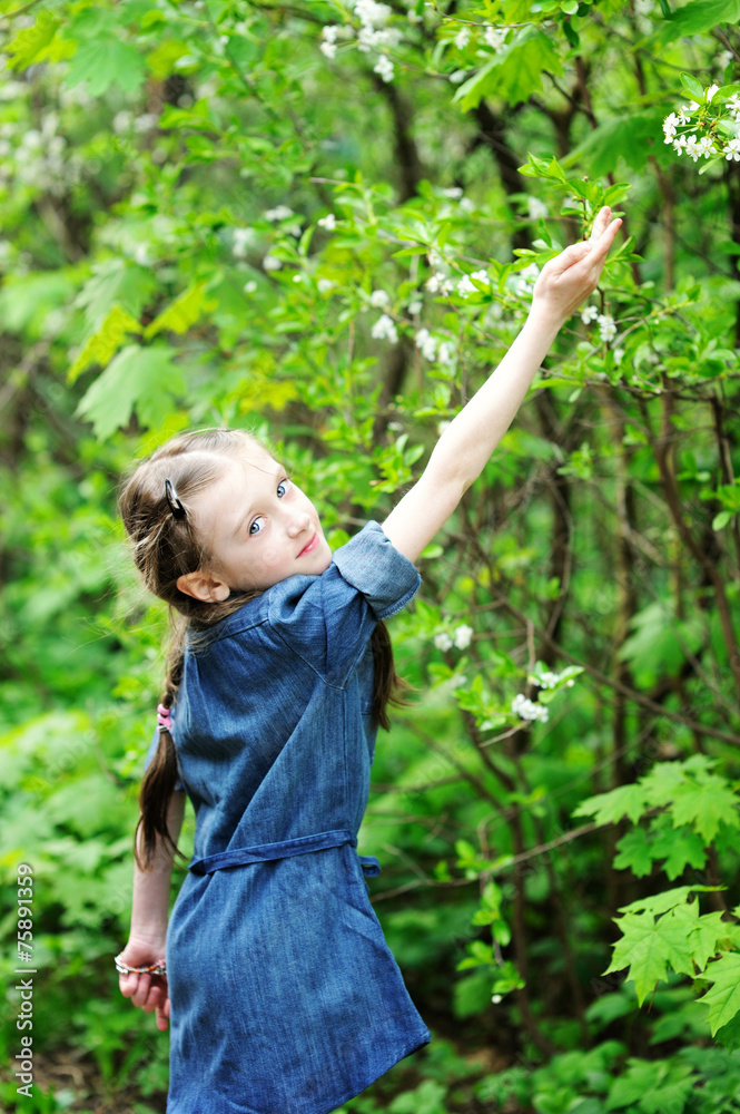 Kid girl in blooming apple tree garden