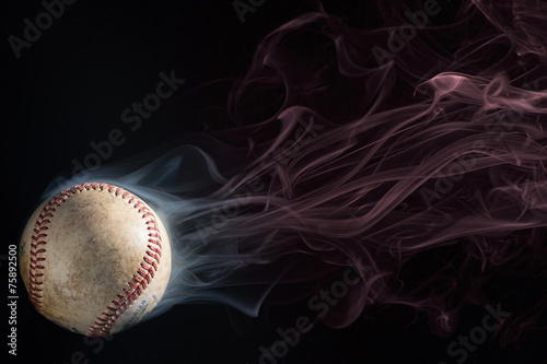 Baseball on black ground with white smoke coming off of it, which then turns to red smoke. Copy Space above the ball. photo