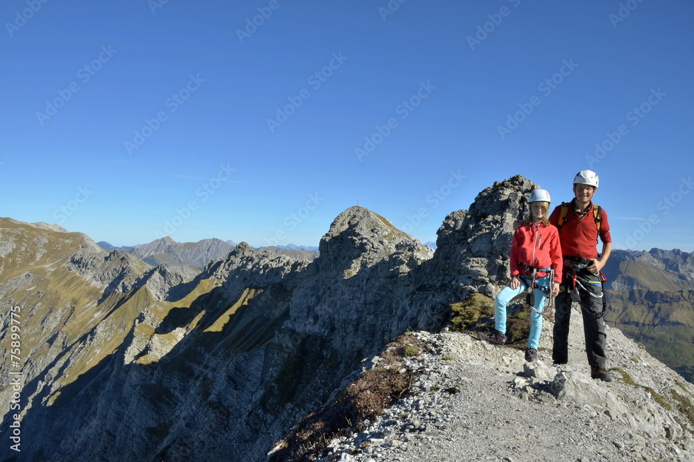 Vater mit Kind beim Klettern am Gipfel