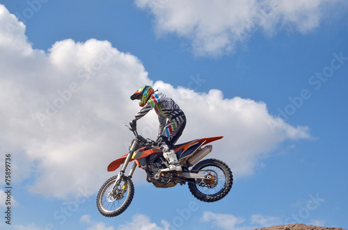 Exstrim driver standing on the MX motorcycle is flying over the