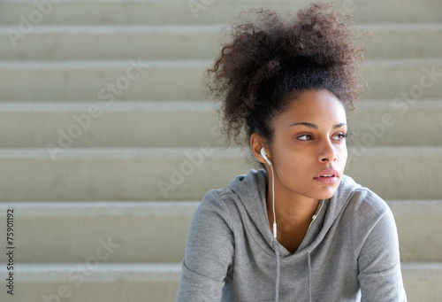 Attractive young sports woman sitting on steps with earphones