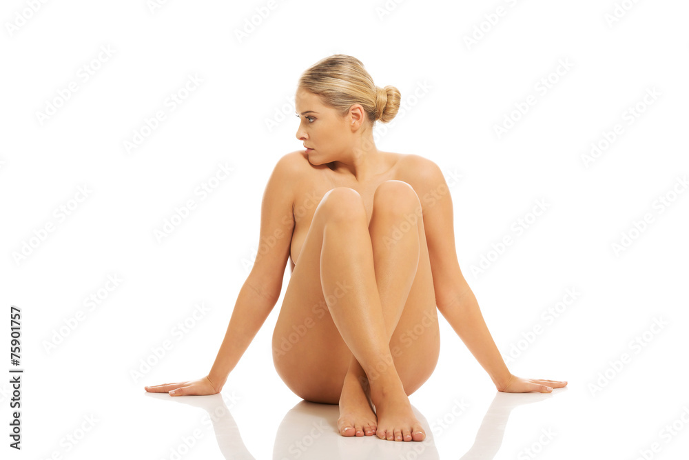 Obraz premium Nude woman sitting on the floor buttres her hands