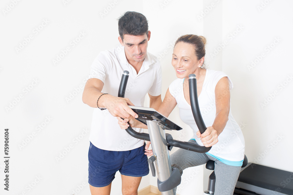 Obraz premium Coach zeigt Frau Fitnessfahrrad