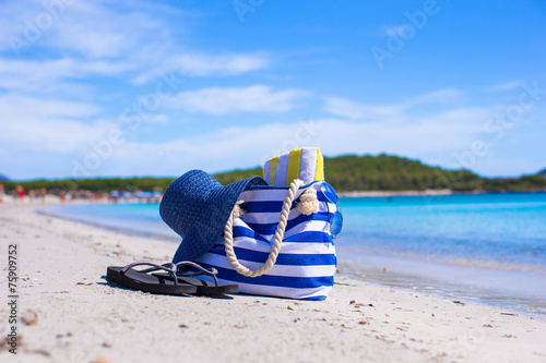 Straw hat, bag and towel on white tropical beach