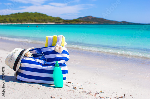 Stripe bag, straw hat, sunblock and towel on beach © travnikovstudio