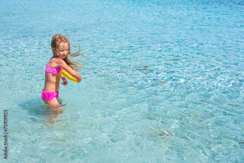 Little girl playing frisbee during tropical vacation in the sea © travnikovstudio