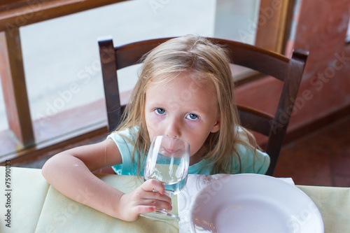 Adorable little girl having breakfast at restaurant